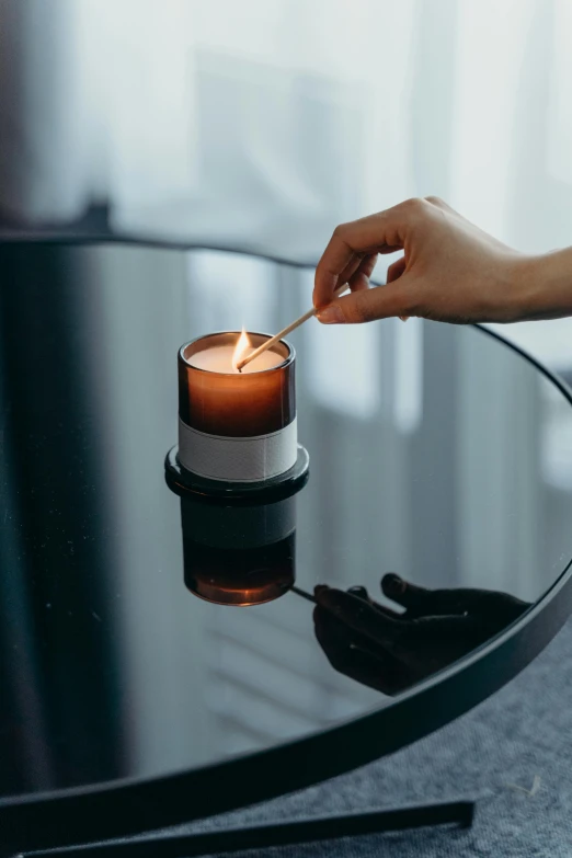 a person lighting a candle on a table, curated collections, umbra, morning time, close angle