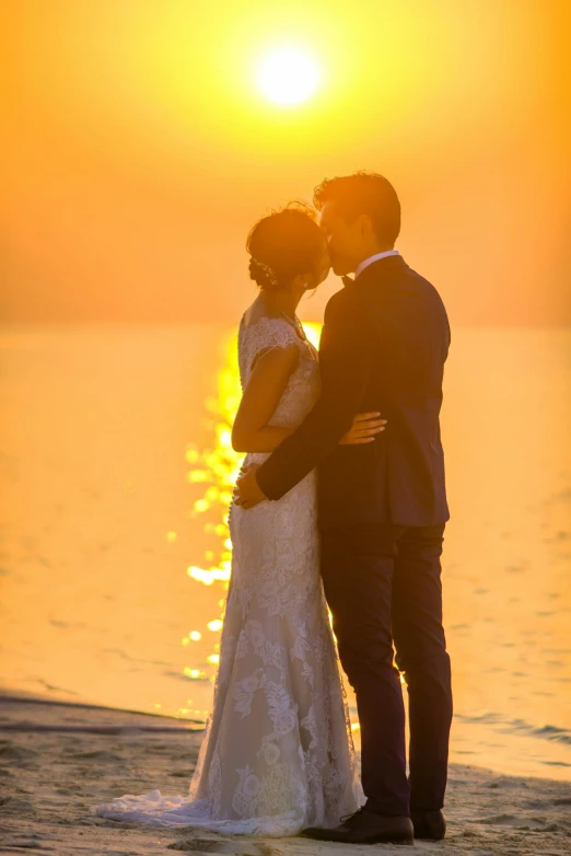 a bride and groom standing on the beach at sunset, ao dai, full morning sun, on the ocean water, kissing