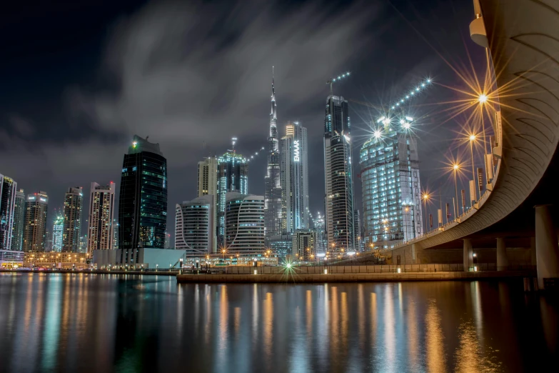 a view of a city at night from the water, pexels contest winner, hyperrealism, sheikh mohammed ruler of dubai, lpoty, photo of futuristic cityscape, construction