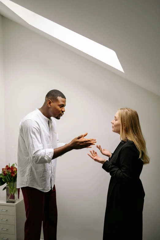 a man standing next to a woman in a room, reaching out to each other, talking, black man, on grey background