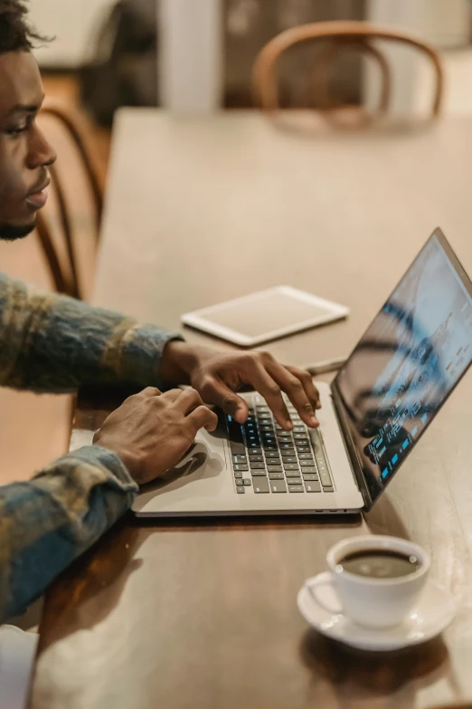 a man sitting at a table using a laptop computer, trending on pexels, afro tech, sitting on a mocha-colored table, thumbnail, center of image