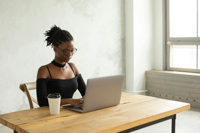 a woman sitting at a table with a laptop, by Carey Morris, trending on pexels, nerdy black girl super hero, wearing a cropped top, slightly minimal, people at work