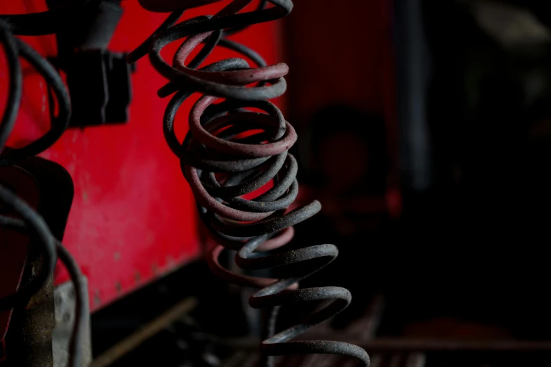 a close up of a bunch of springs on a machine, an album cover, by David Simpson, unsplash, black and red, working in the forge, vine twist, high resolution print :1 red