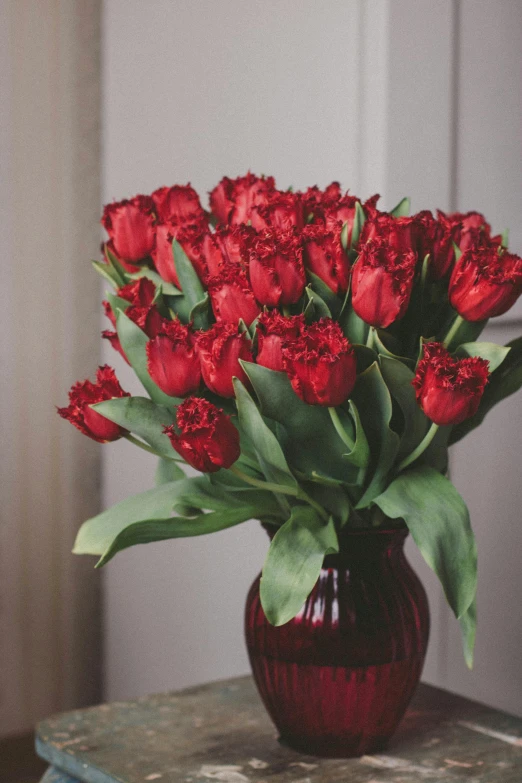 a red vase filled with lots of red flowers, inspired by Valentine Hugo, shutterstock contest winner, tulips, maroon metallic accents, elegant atmosphere, tufted softly