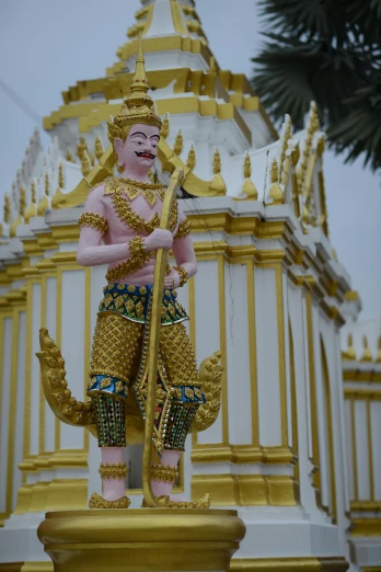 a statue of a man holding a staff, pink and gold color scheme, cambodia, ornate spikes, 2019 trending photo