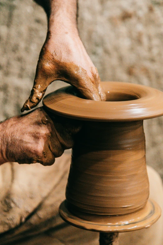 a person making a clay pot on a potter's wheel, an abstract sculpture, inspired by Hendrik Gerritsz Pot, trending on unsplash, oman, thumbnail, brown, made out of clay
