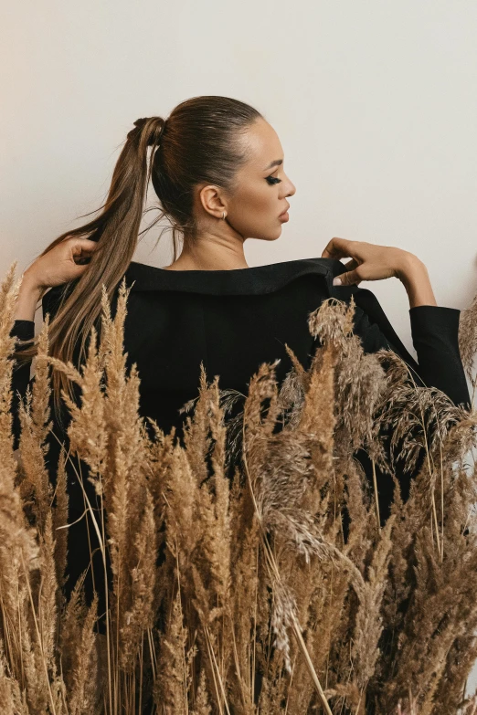 a woman standing in a field of tall grass, trending on pexels, aestheticism, black sweater, ponytail, studio photo, dried plants