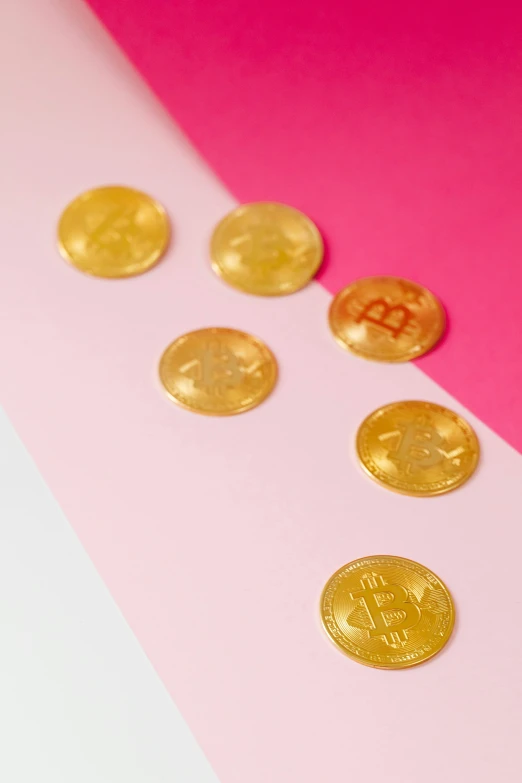 a bunch of gold coins sitting on top of a pink and white surface, edible crypto, product photograph, made of candy, tan