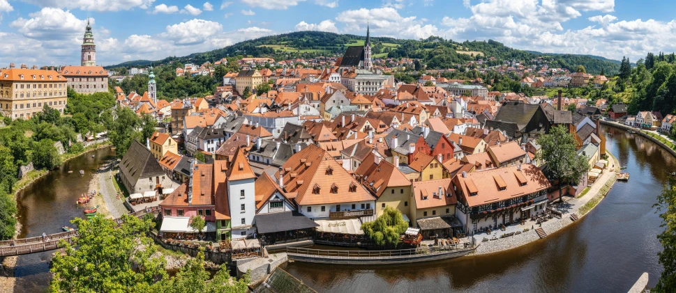 a river running through a town next to a lush green hillside, baroque, orange roof, matej ‘retro’ jan, square, ultrawide image