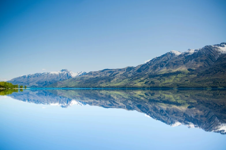 a large body of water with mountains in the background, by Peter Churcher, pexels contest winner, minimalism, new zeeland, blue reflections, mirrored, istockphoto