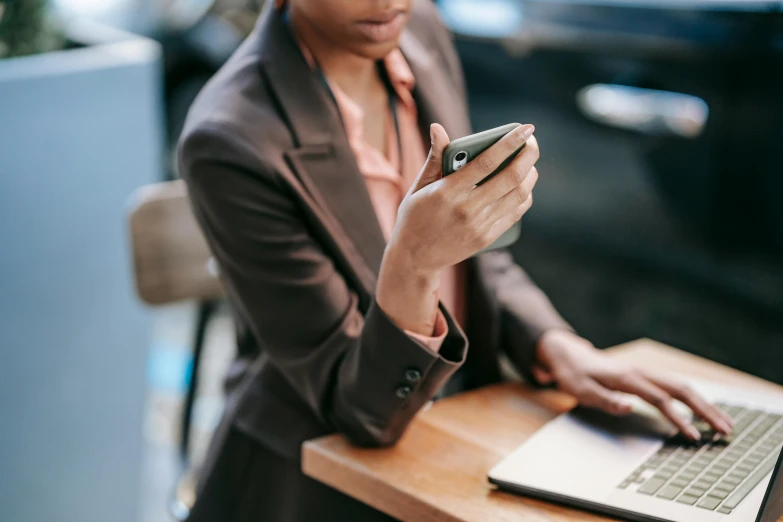 a woman sitting at a table using a cell phone, trending on pexels, wearing a worn out brown suit, avatar image, typing on laptop, thumbnail