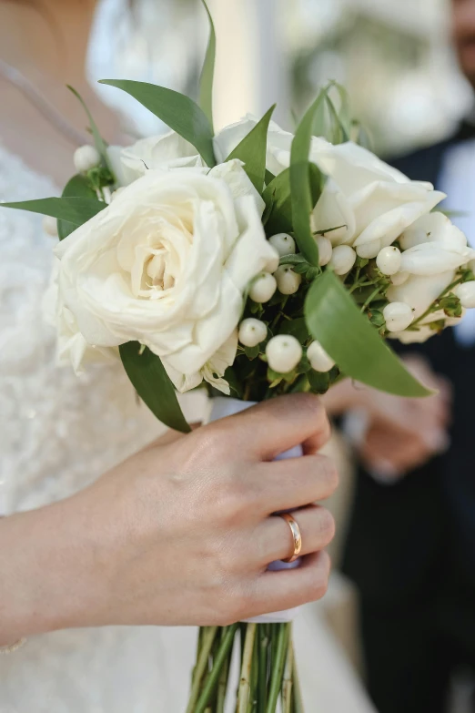 a close up of a person holding a bouquet of flowers, white with gold accents, petite, couple, f / 2 0