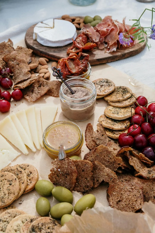 a table topped with lots of different types of food, cheeses, on a wooden plate, 2019 trending photo
