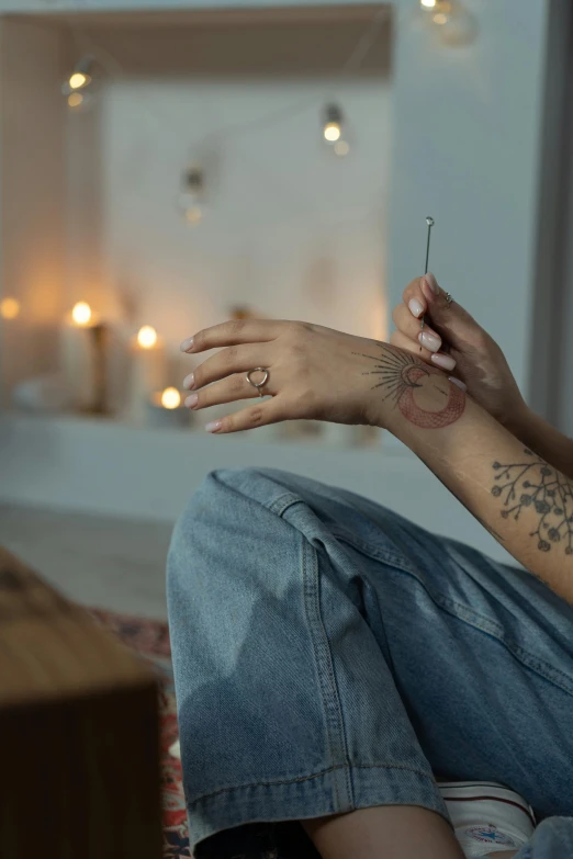 a woman sitting on a couch holding a cigarette, a tattoo, inspired by Elsa Bleda, trending on pexels, natural candle lighting, meditation pose, silver and muted colors, holding a magic needle