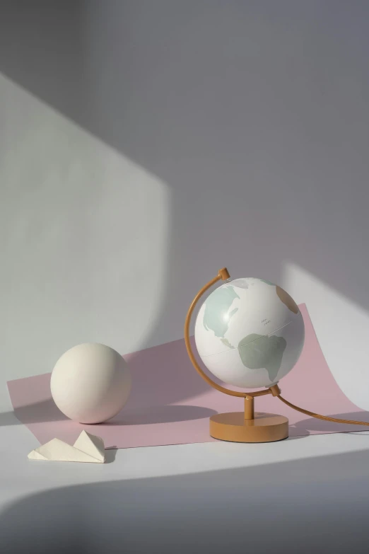 an egg sitting on top of a table next to a globe, earthy light pastel colours, matte surface, eucalyptus, halo / nimbus