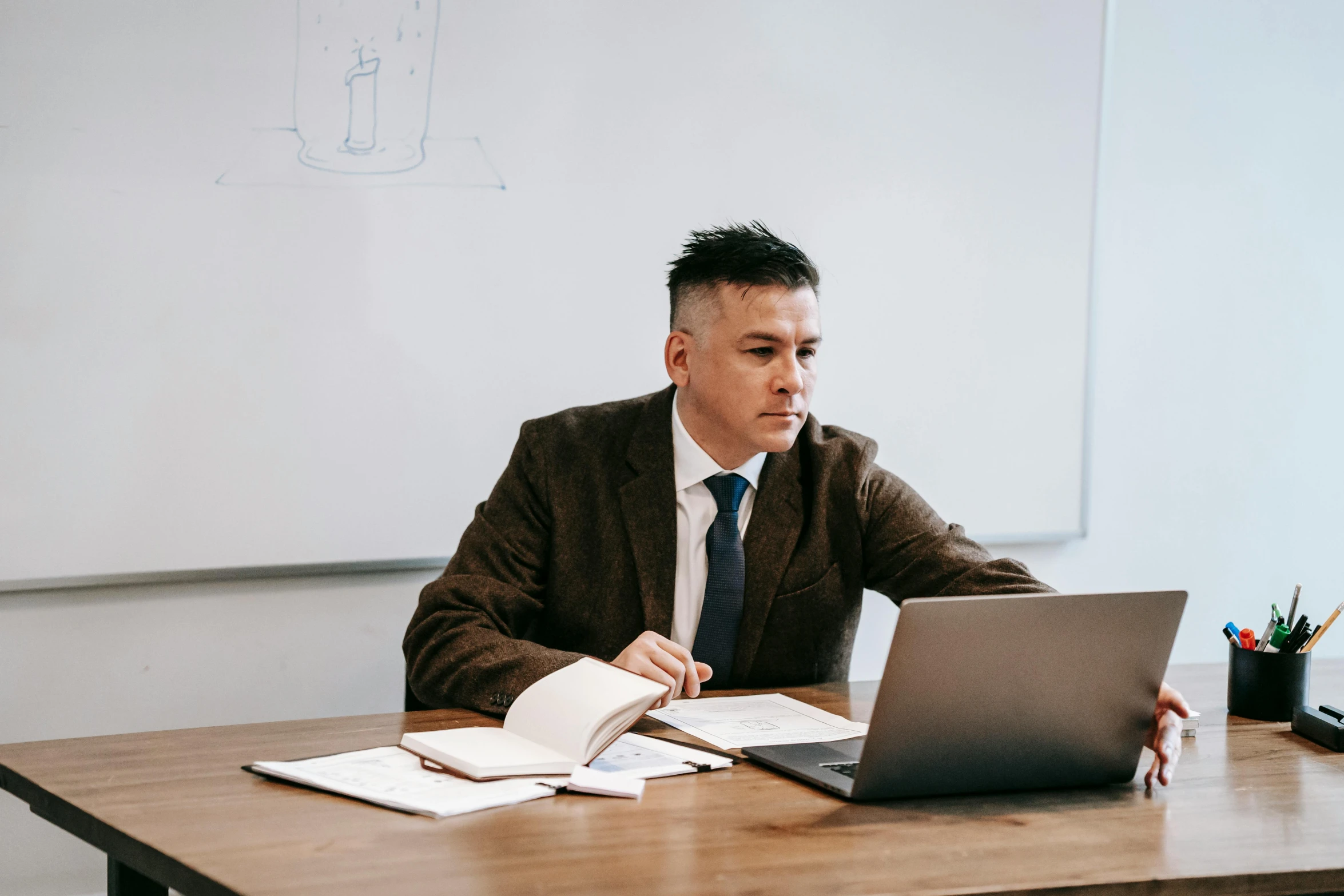 a man sitting at a desk in front of a laptop computer, unsplash, teacher, lawyer clothing, te pae, darren quach