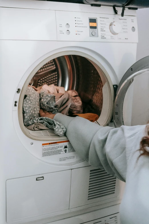 a woman putting clothes into a washing machine, by Matija Jama, pexels contest winner, dusty space suit, low quality footage, australian, profile image