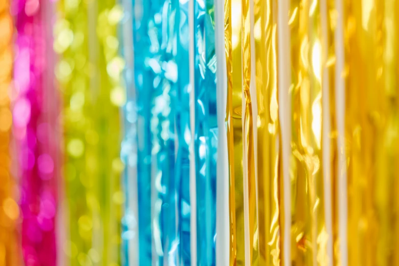 a close up of a rainbow colored curtain, by Julia Pishtar, plasticien, yellow and blue ribbons, foil effect, defocused bars in the foreground, decorative lines