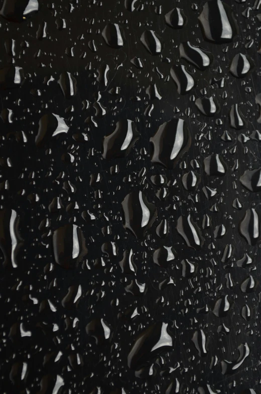 a close up of water droplets on a black surface, by david rubín, conceptual art, vinyl material, black main color, panel of black, made of smooth black goo