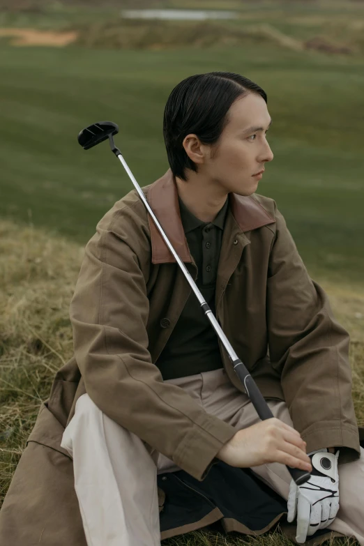 a man sitting on the ground with a golf club, inspired by Fei Danxu, unsplash, renaissance, wearing a turtleneck and jacket, promo image, hammershøi, album cover