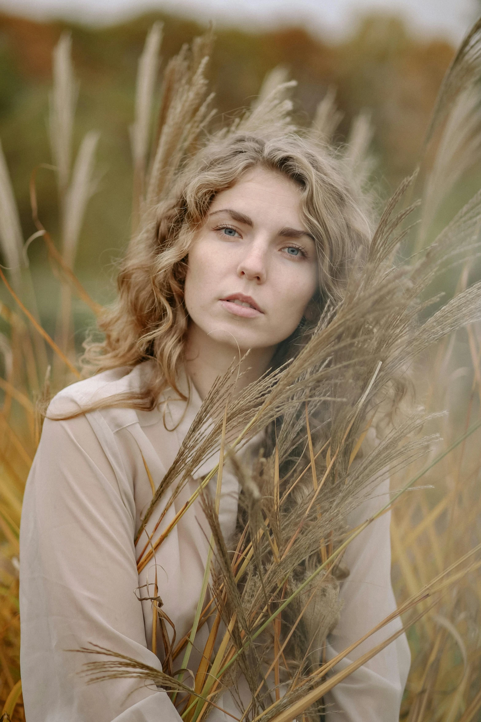 a woman sitting in a field of tall grass, inspired by Elsa Bleda, renaissance, short golden curls, muted browns, wearing hay coat, promo image