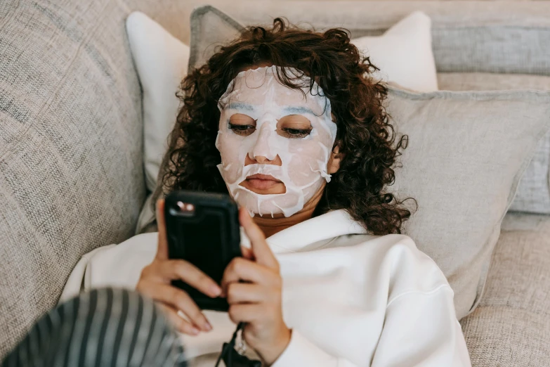 a woman laying on a couch using a cell phone, trending on pexels, happening, face mask, avatar image, bedhead, silicone skin