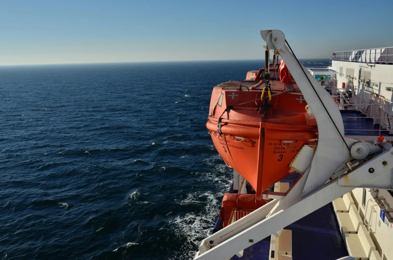 a large red boat in the middle of the ocean, in the distance, helmet view, looking out over the sea, seraphine