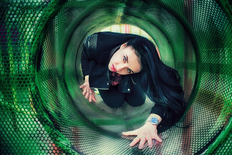 a woman standing inside of a green metal tube, an album cover, crawling towards the camera, yulia nevskaya, all enclosed in a circle, profile image