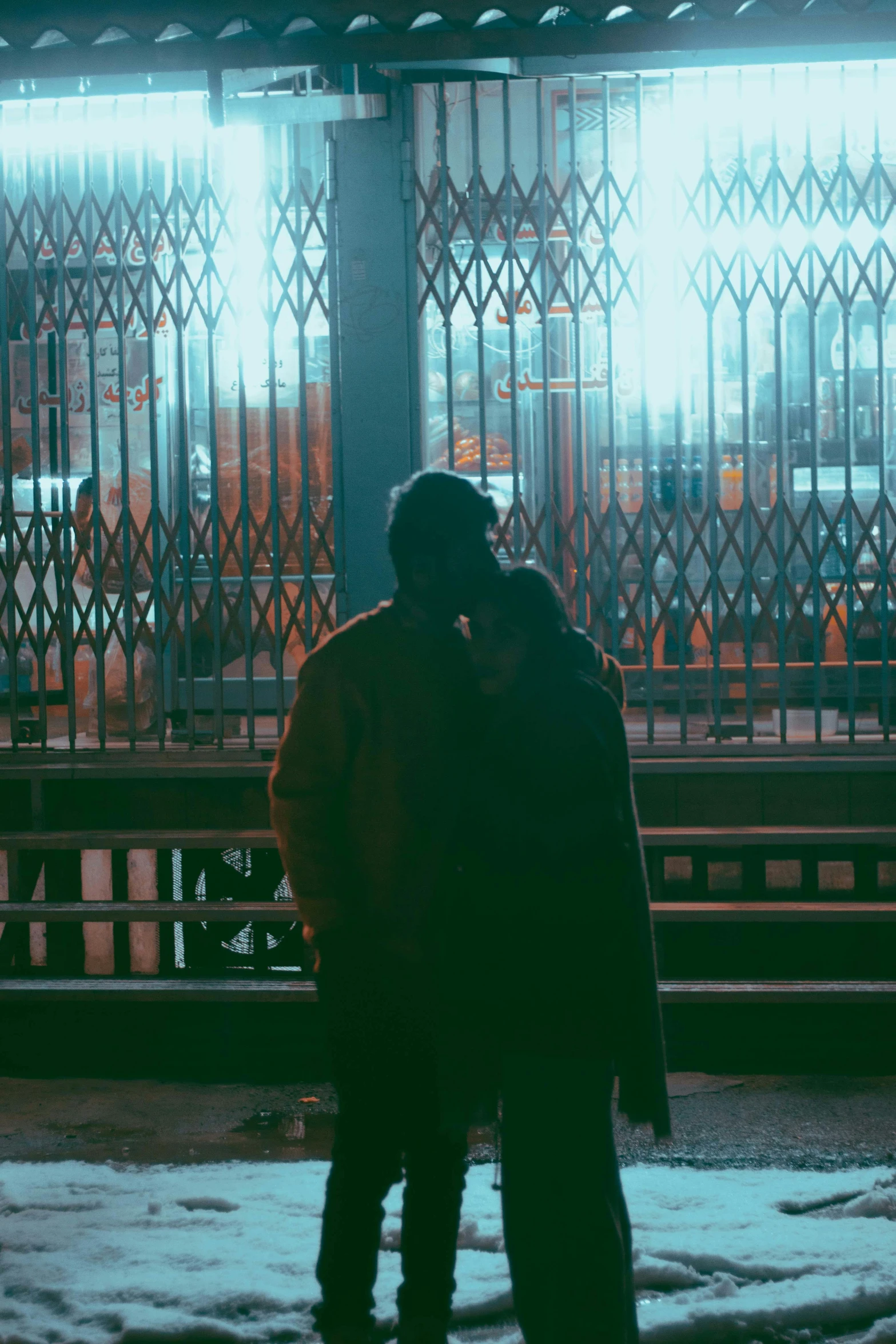 a couple standing next to each other in the snow, inspired by Elsa Bleda, pexels contest winner, happening, dark city bus stop, behind bars, ( ( theatrical ) ), facing away