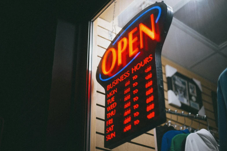 a neon sign hanging from the side of a building, pexels, retail price 4 5 0, open door, electronic case display, owen gent