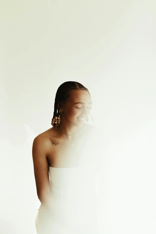 a woman in a white dress standing in front of a white wall, by Dulah Marie Evans, pexels contest winner, happening, wiz khalifa, light falling on face, smiling, mists