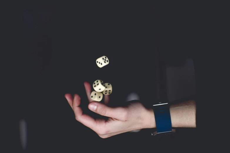 a person holding two dice in their hand, by Matthias Stom, unsplash, visual art, floating objects, ad image, watch photo, dimly - lit