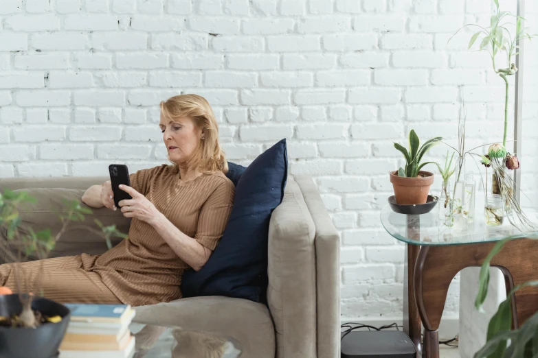 a woman sitting on a couch using a cell phone, a photo, trending on pexels, looking old, looking around a corner, well proportioned, integrating with technology