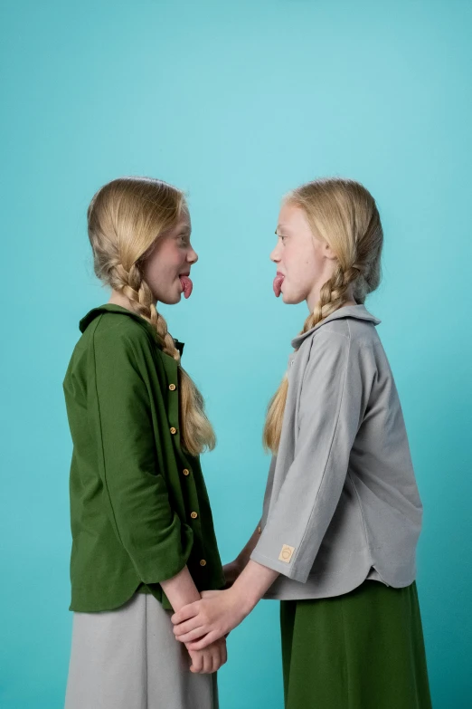 two little girls standing next to each other, inspired by Elsa Beskow, unsplash, pop art, licking out, in a dark green polo shirt, grey backdrop, facing each other