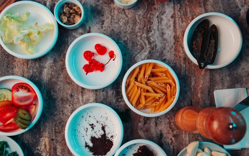 a wooden table topped with bowls of food, pexels, renaissance, background image, pasta, desert, chewing tobacco