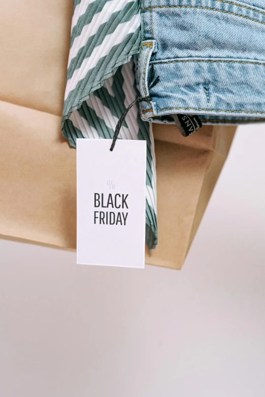 a person holding a brown paper bag with a black friday tag on it, by Sam Black, trending on unsplash, wearing festive clothing, thumbnail, denim, main colour - black