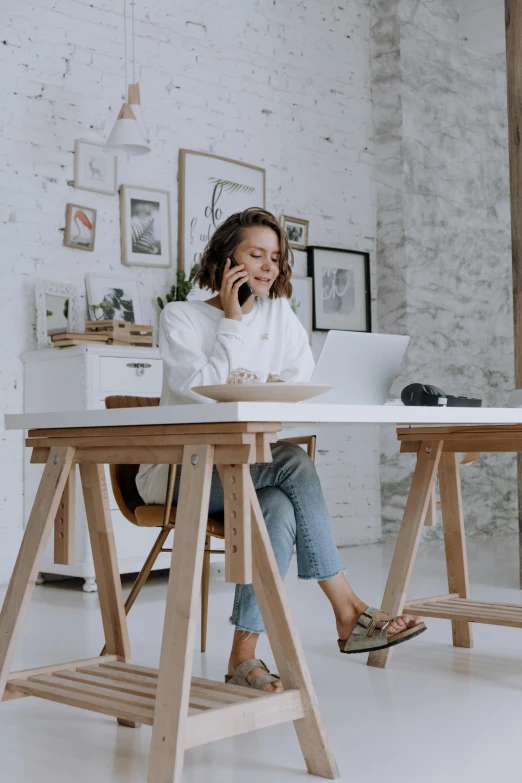 a woman sitting at a desk talking on a cell phone, pexels contest winner, white shirt and jeans, exploration, cool marketing photo, working