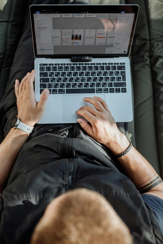 a man laying on a couch using a laptop computer, by Carey Morris, pexels, looking down from above, hunting, sleek hands, maintenance photo