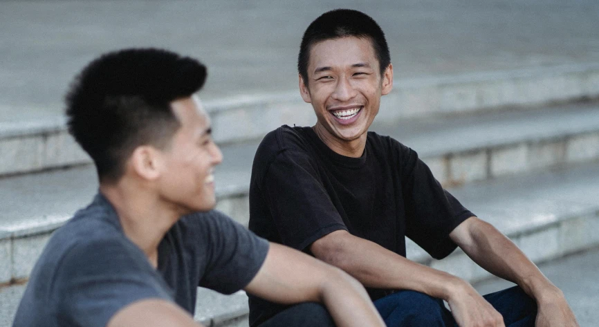 a couple of men sitting next to each other, inspired by Tooth Wu, pexels contest winner, happening, smiling male, half asian, thin young male, with black