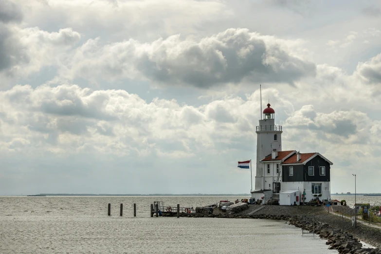 a lighthouse in the middle of a body of water, a picture, by Jan Tengnagel, pexels contest winner, delftware, grey sky, sunny sky, thumbnail