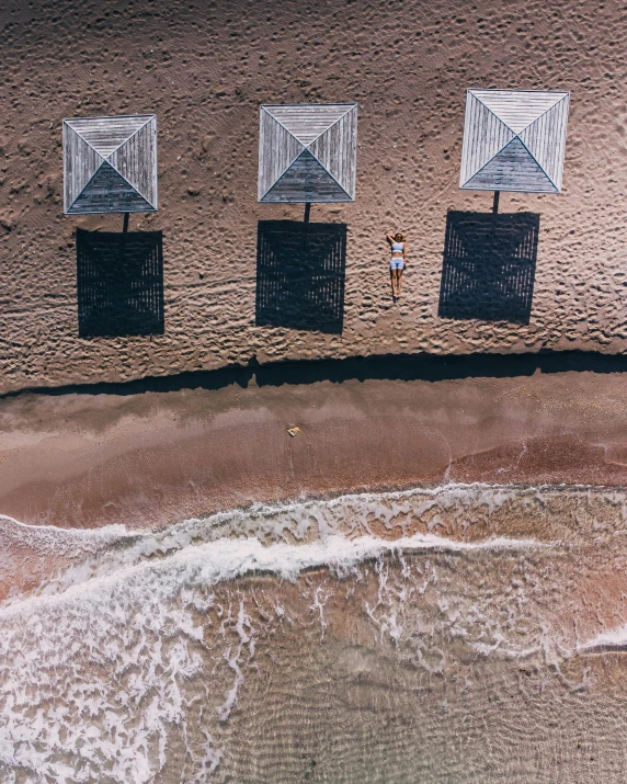 a couple of umbrellas sitting on top of a sandy beach, by Arabella Rankin, unsplash contest winner, bird's - eye view, triptych, bali, gif