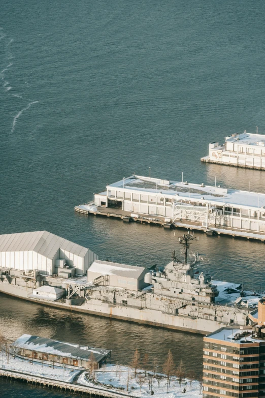 a harbor filled with lots of boats next to tall buildings, trending on unsplash, modernism, military carrier rig, hangar, seen from above, museum photo