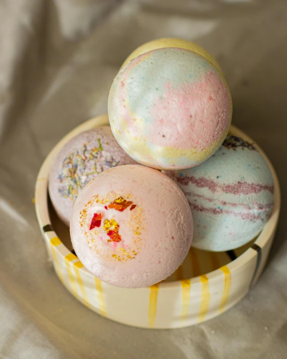 three bath bombs stacked on top of each other in a bowl, a pastel, inspired by Eden Box, balls of fire, malaysian, on a wooden tray, close portrait