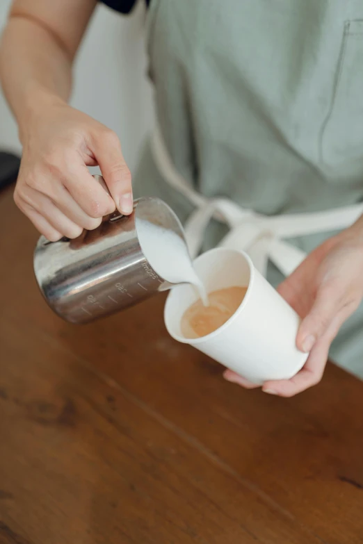 a woman pouring a cup of coffee into a cup, unsplash, neoprene, detailed product image, white sleeves, with highly detailed