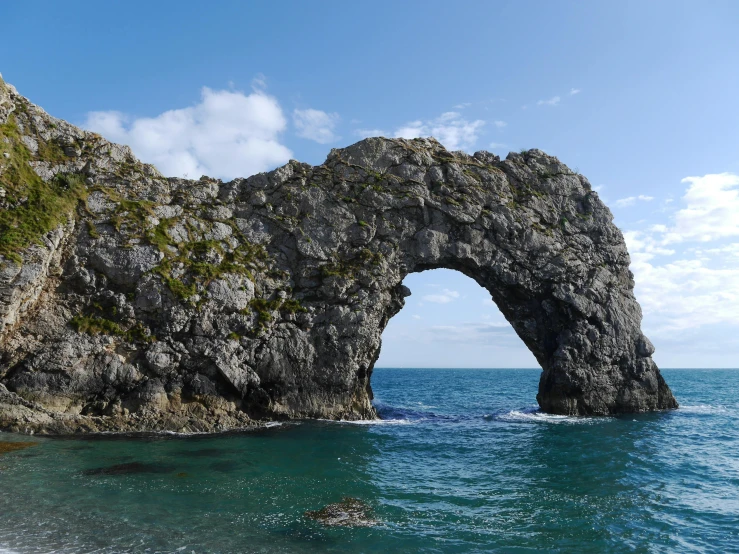 a large rock formation in the middle of a body of water, archway, great britain, clear blue water, slide show