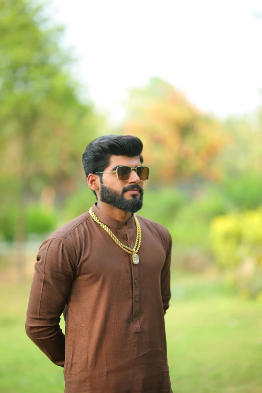 a man standing in a field wearing a brown shirt, by Max Dauthendey, pexels contest winner, hurufiyya, wearing gold jewellery, oak leaf beard, jayison devadas style, ( ( theatrical ) )