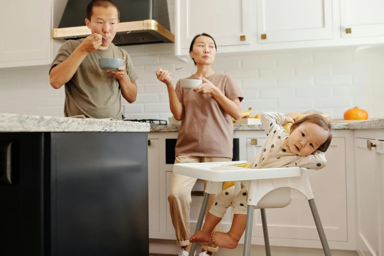 a man and woman standing in a kitchen with a baby in a high chair, pokimane, people panicking, asian human, innovation