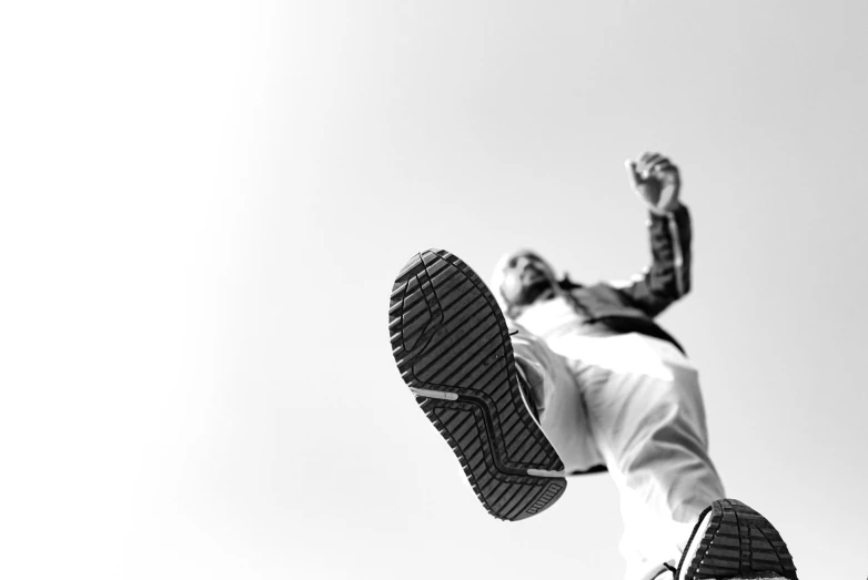 a man flying through the air while riding a skateboard, a black and white photo, by Mathias Kollros, unsplash, conceptual art, sneaker made out of lego, view from below, high details photo, white shoes