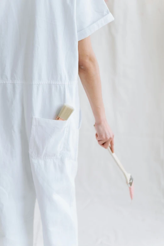 a woman is brushing her teeth with a toothbrush, an album cover, inspired by Agnes Martin, unsplash, jumpsuit, detail, holster, white