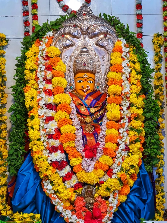 a close up of a statue of a person surrounded by flowers, samikshavad, avatar image, blue colored traditional wear, square, high quality photo